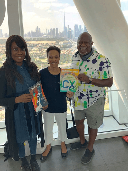 Three people posing in front of skyscraper
