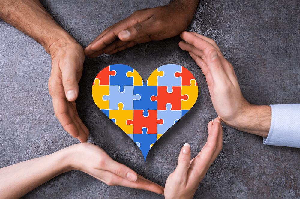 Toastmasters International, autistic members, hands around heart, autism awareness, colored puzzle pieces Hands around heart filled with colored puzzle pieces