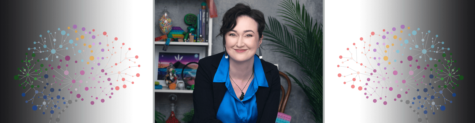 Woman in blue collared shirt and black suit jacket sitting and smiling