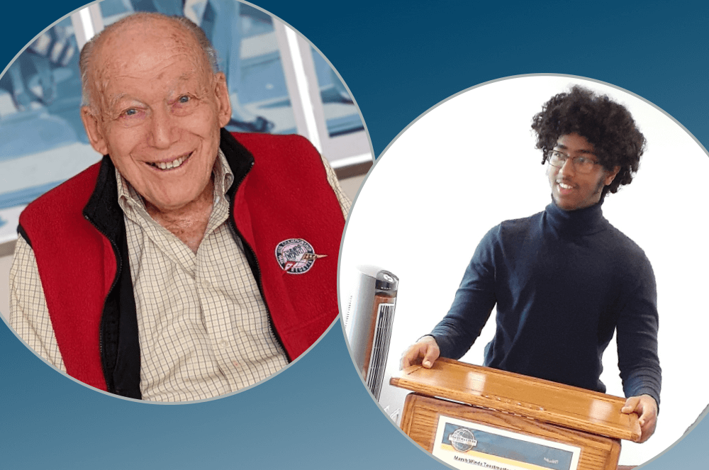 Ninety-six-year-old man smiling in red vest and eighteen-year-old man in blue turtleneck standing at lectern