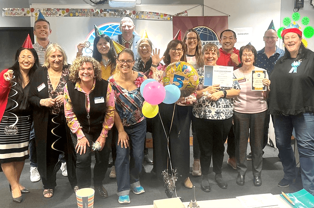 Group of people posing with balloons and party hats