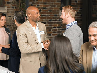 Two men shaking hands at a Toastmasters Open House