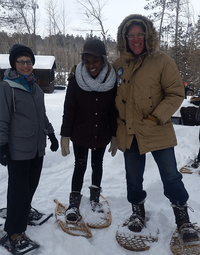 Minnesota Returned Peace Corps Volunteers Toastmasters Amy Earle, Phoebe Munene and Dan Grundtner pose outdoors in snowshoes on a club outing. Munene joined MRPCV as an agriculture student at the University of Minnesota.