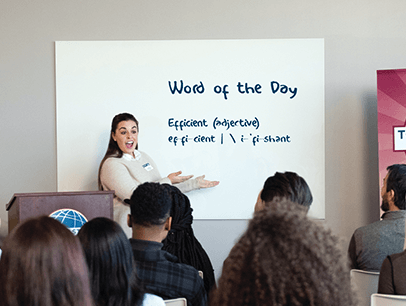 Woman stands in front of white board at Toastmasters meeting