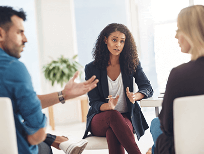 One male and two females sitting and talking