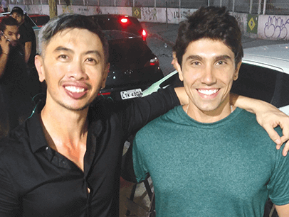 Man in black shirt poses with man in green shirt