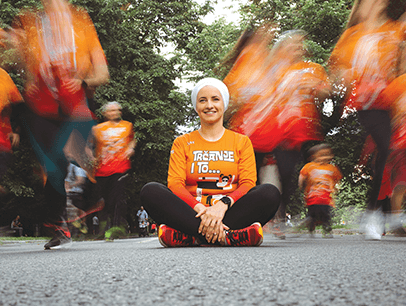 Woman in orange shirt sitting on pavement