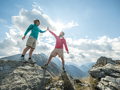 Man and woman high-five on top of mountain