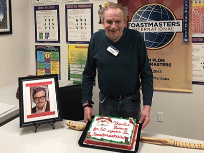 Man posing with banner and cake