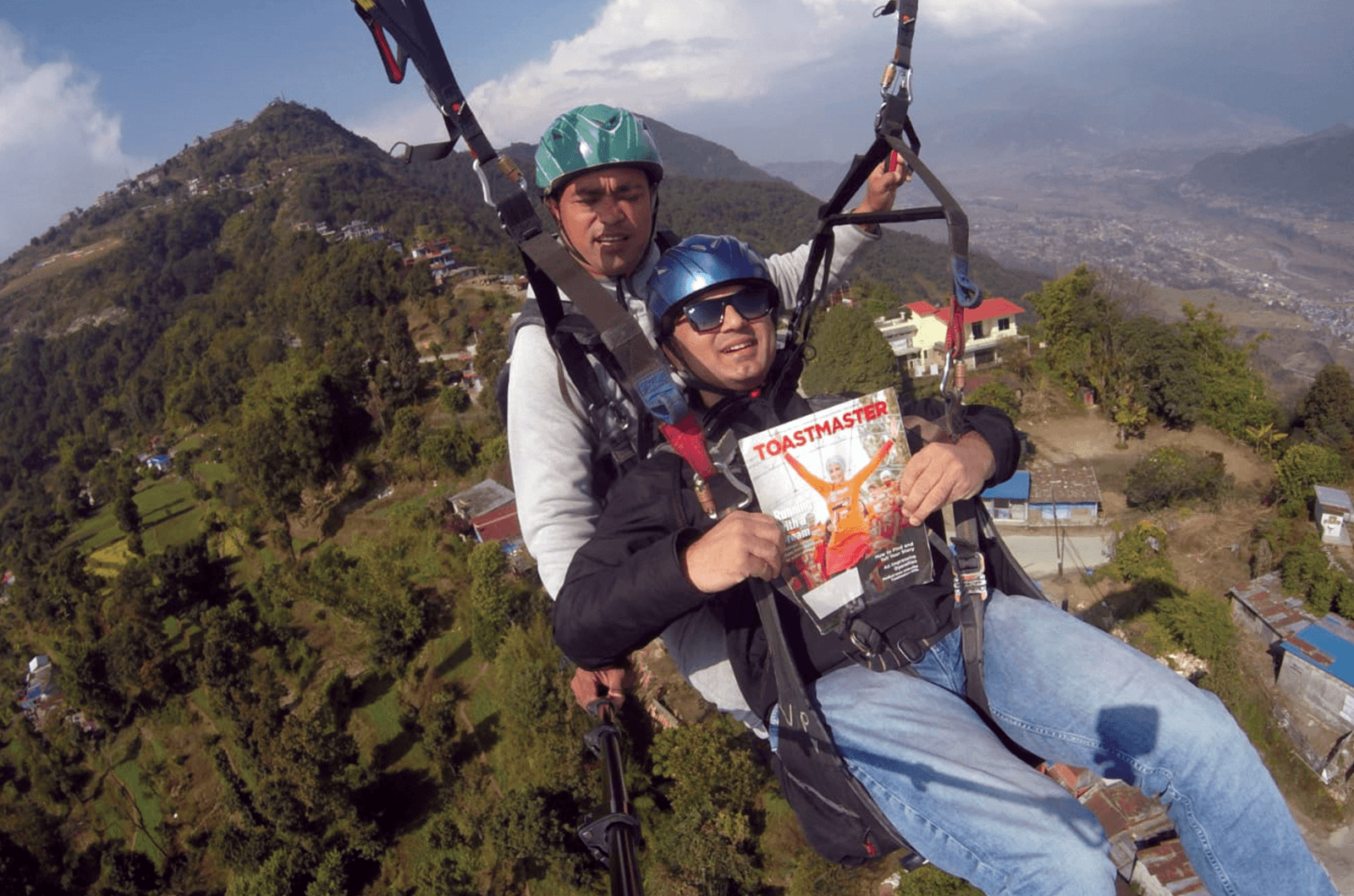 Ajay Kumar Mohapatra of Pune, Maharashtra, India, paraglides with his magazine and an instructor in Pokhara, Nepal.