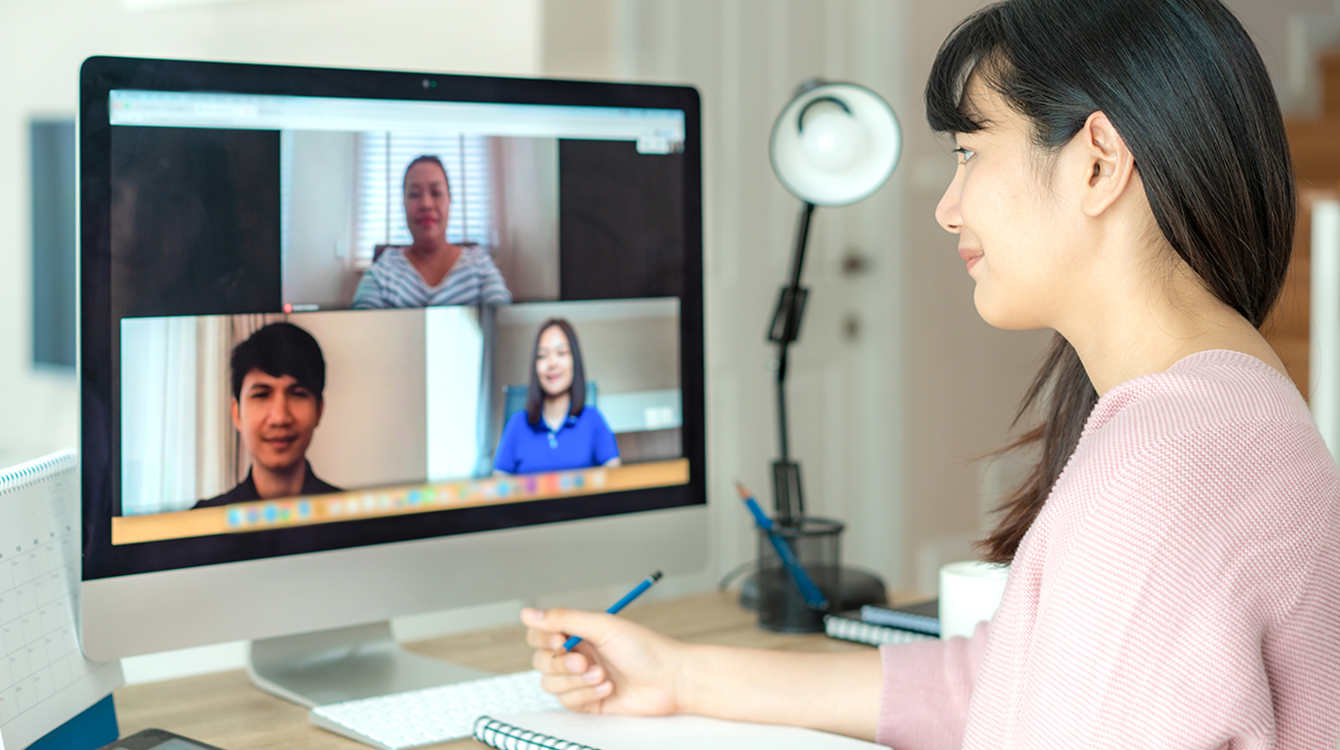 Woman in pink shirt smiling at three people on computer screen