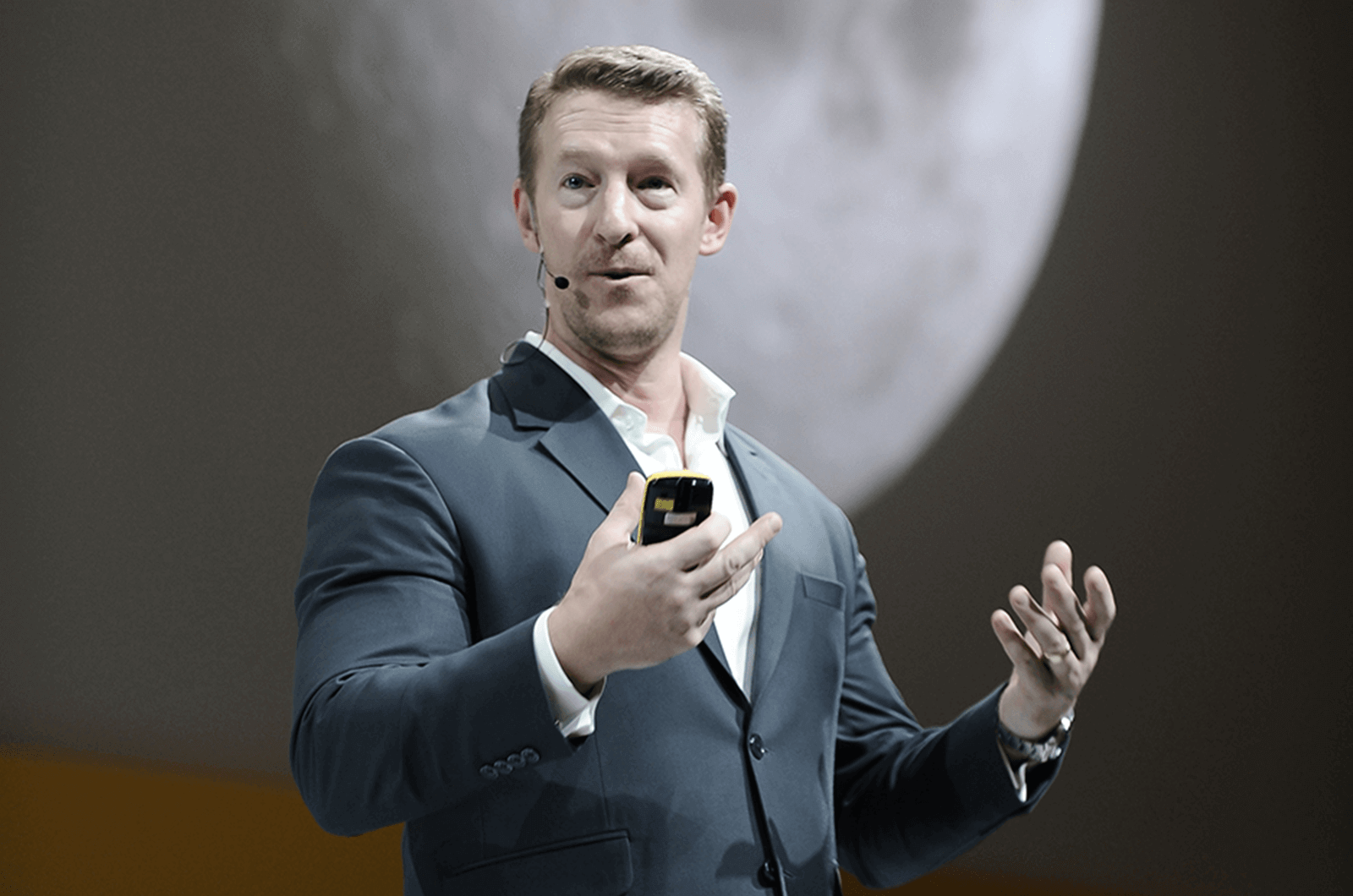 Douglas Kruger speaking onstage using hand gestures