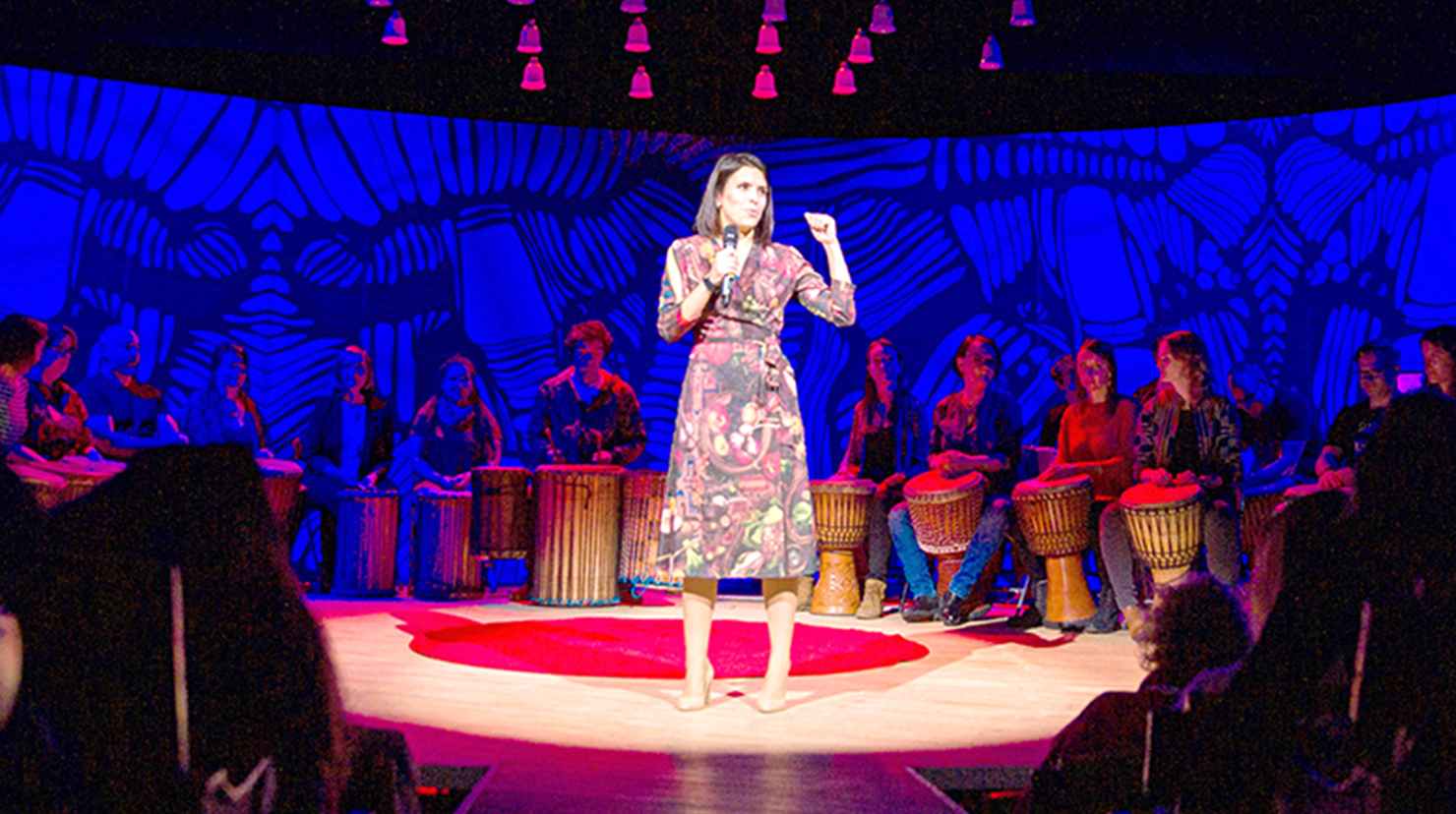 Elena Paweta giving speech on red dot on TEDx stage