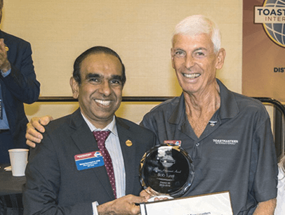 Toastmasters International President Deepak Menon awards member Bob Turel a certificate