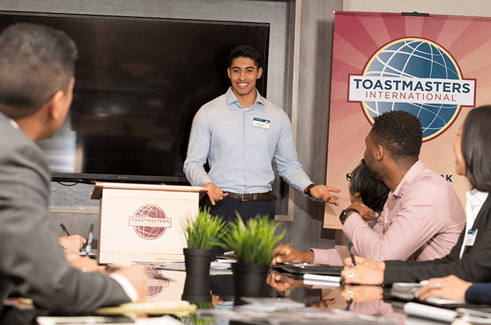 Man standing at lectern speaking at Toastmasters meeting