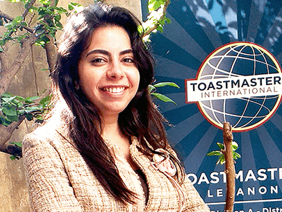 Woman in jacket and jeans posing next to banner