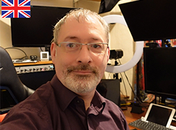 Man looking at camera with computer screens in background