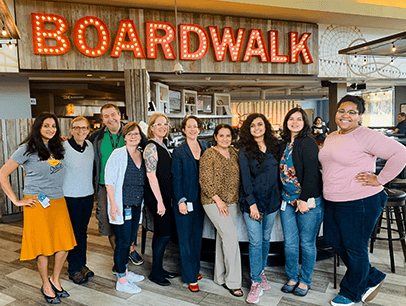 Group of people posing under lit up boardwalk sign