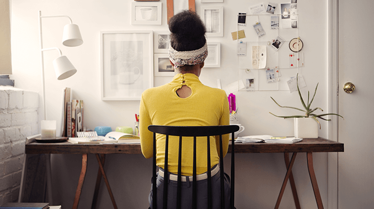 Woman in yellow sweater working at desk at home