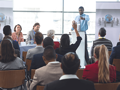 Man standing up pointing at audience member with hand up