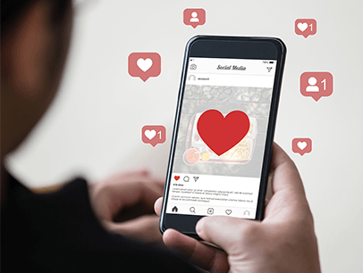 Social media hearts and thumbs up next to someone on smartphone