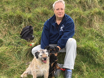 Man sitting outside in grass with two dogs